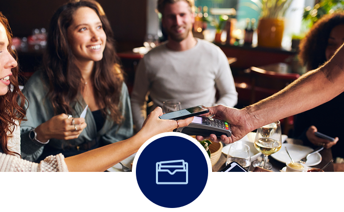 Group of young people at dinner, paying on a mobile payment device.