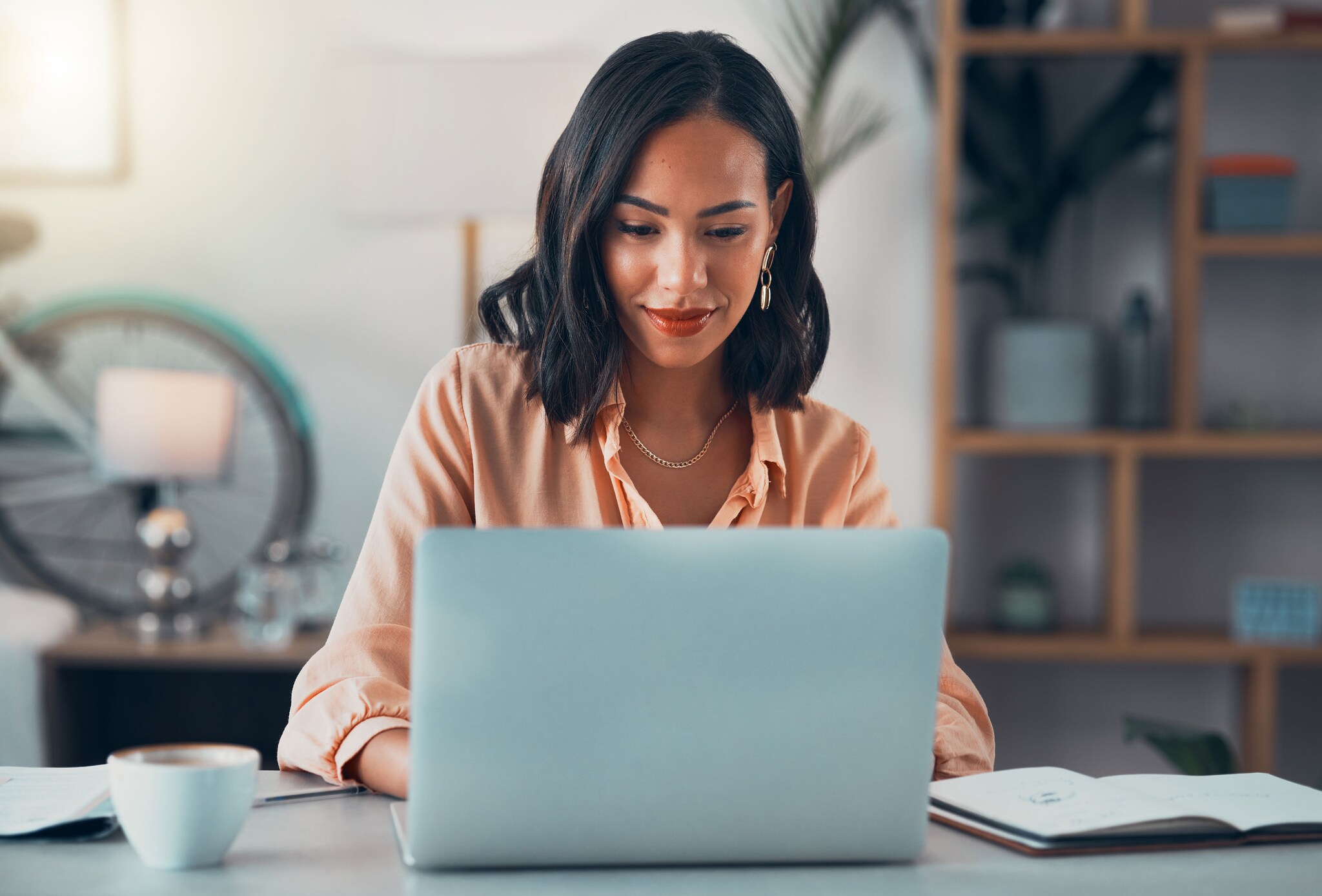 Woman working on laptop online, checking emails and planning on the internet while sitting in an office alone at work.