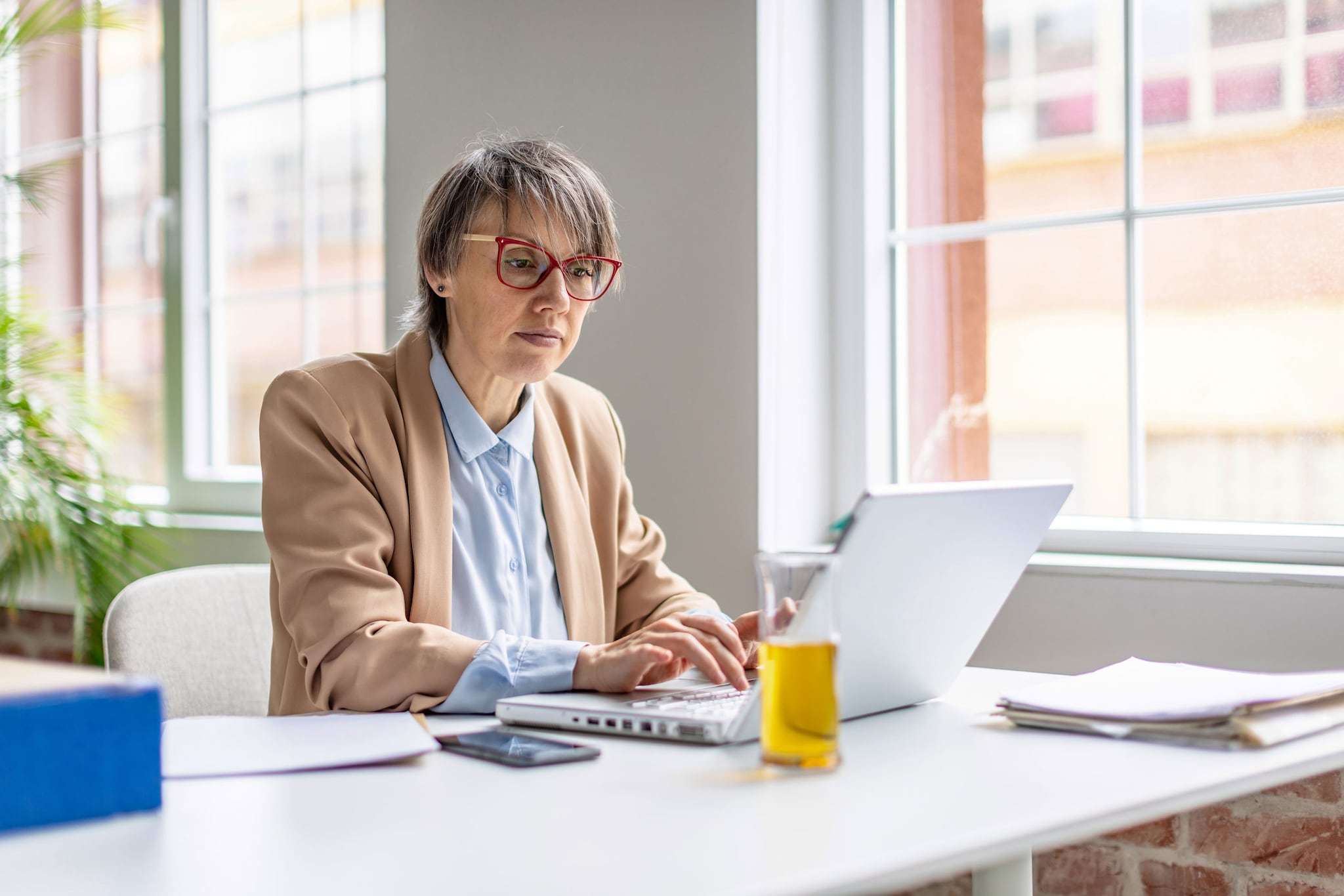 A woman is engaged in work using her laptop in a bright, inviting office environment.
