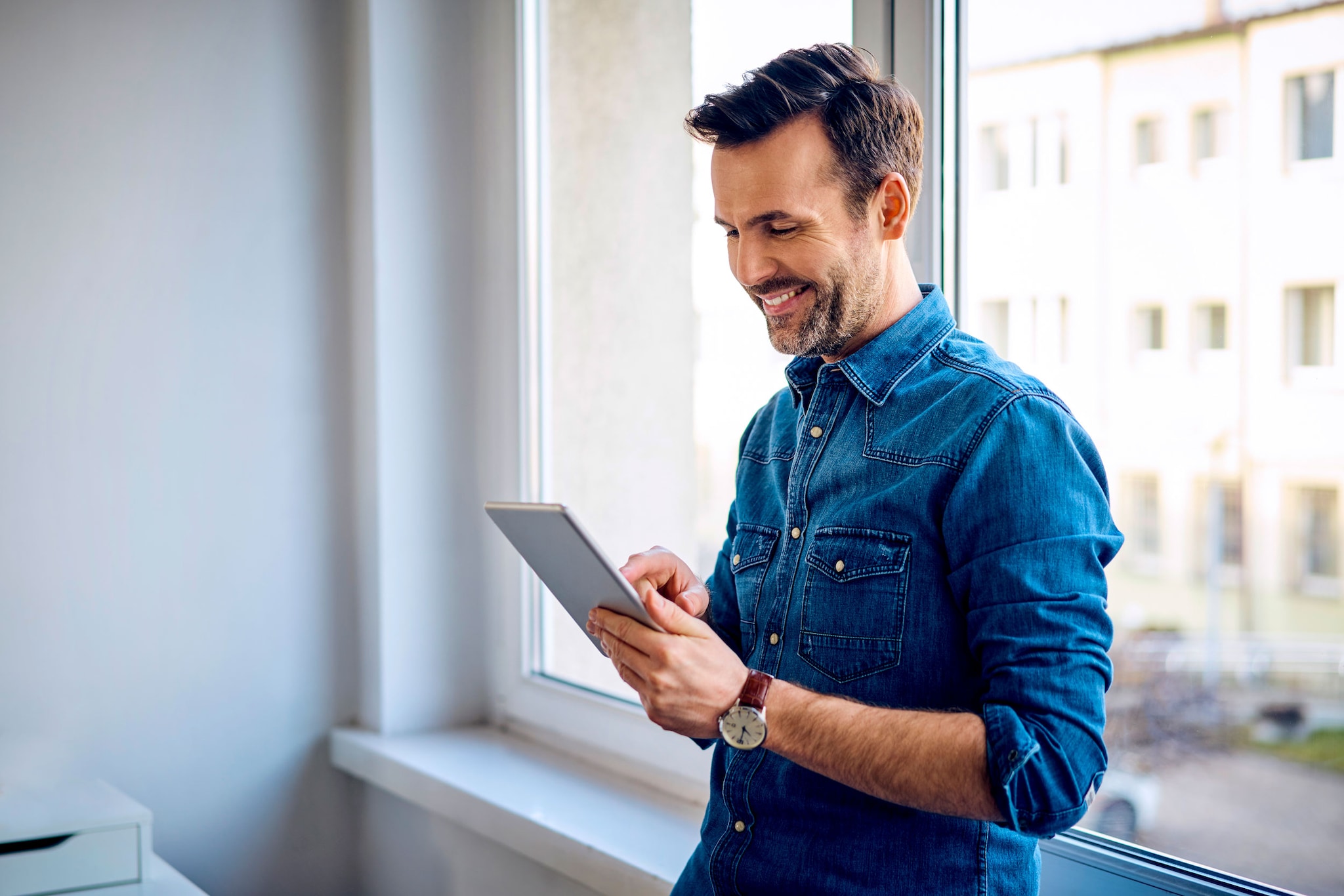 Smiling man interacting with his digital tablet.