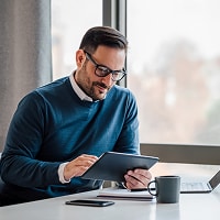 Man looking at ipad, representing identity protection and credit monitoring with CreditSecure