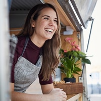 Woman happy and carefree looking outside of a food truck, representing free credit monitoring with MyCredit Guide