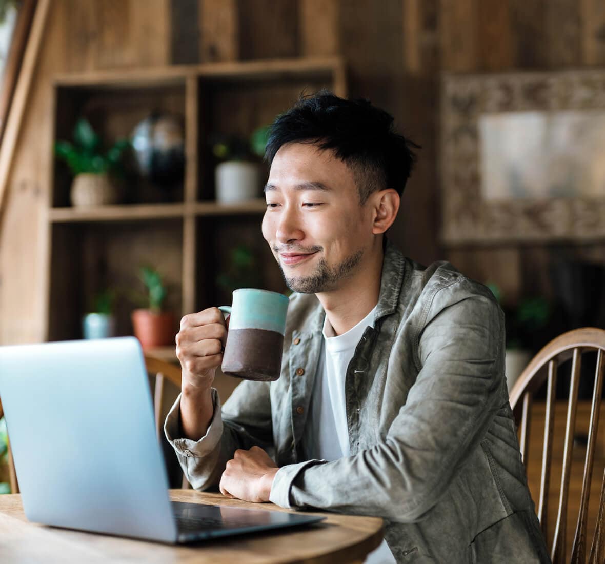 Person holding mug looking at laptop