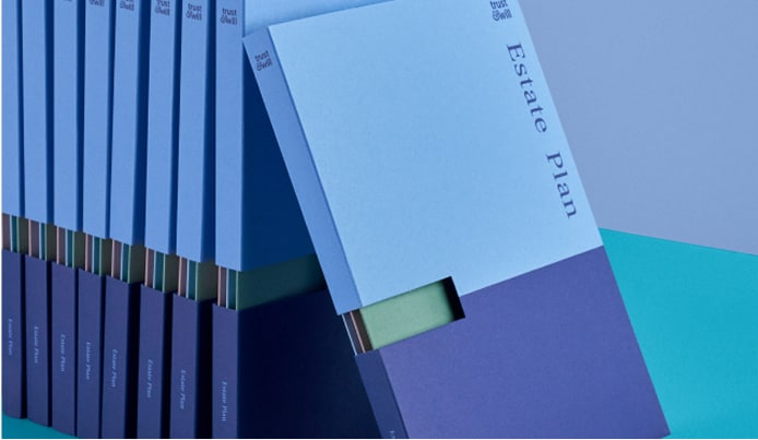 Stack of Trust & Will estate plan booklets in blue with one booklet leaning forward.