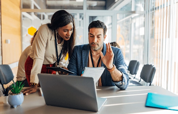 A woman and man study paperwork and computer files in a conference room