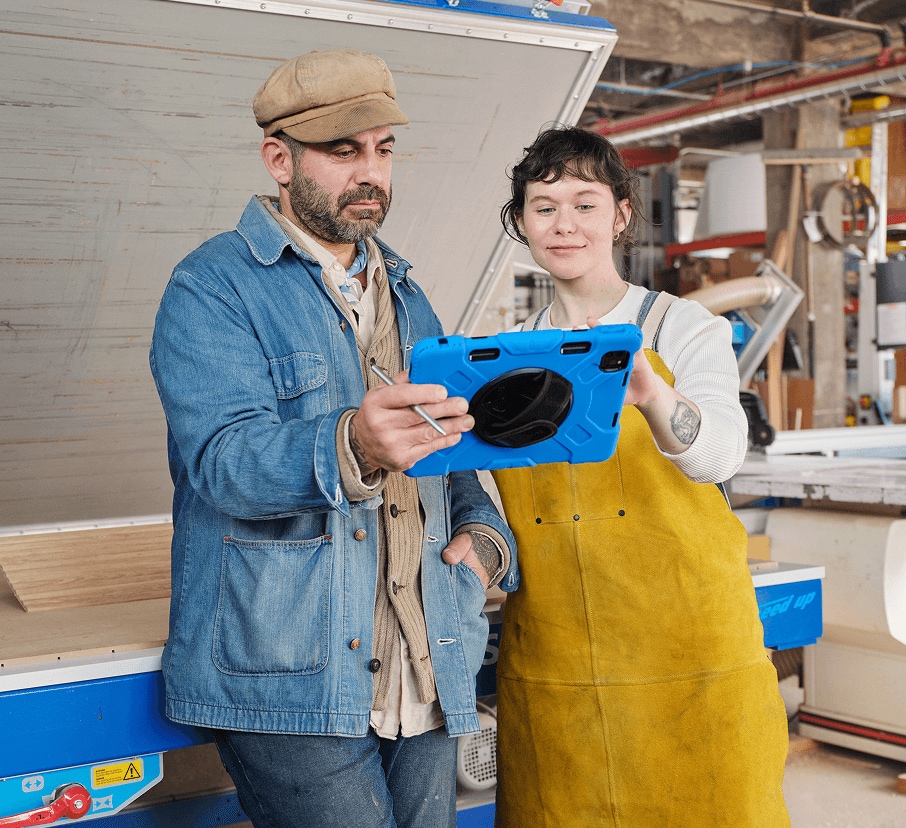 Two coworkers study a tablet in a workshop