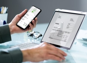 Person looking at invoice on laptop and holding mobile device