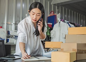 Person in inventory room talking on the phone and writing something down