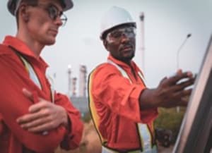 Two workers with hard hats looking at board