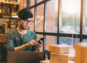 Person at table with laptop and looking at phone