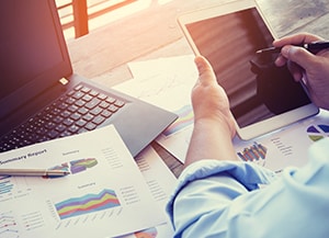 person looking at tablet device with print out of data trends next to them
