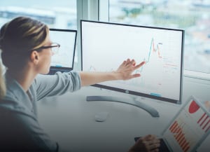 Person pointing to data label on desktop monitor