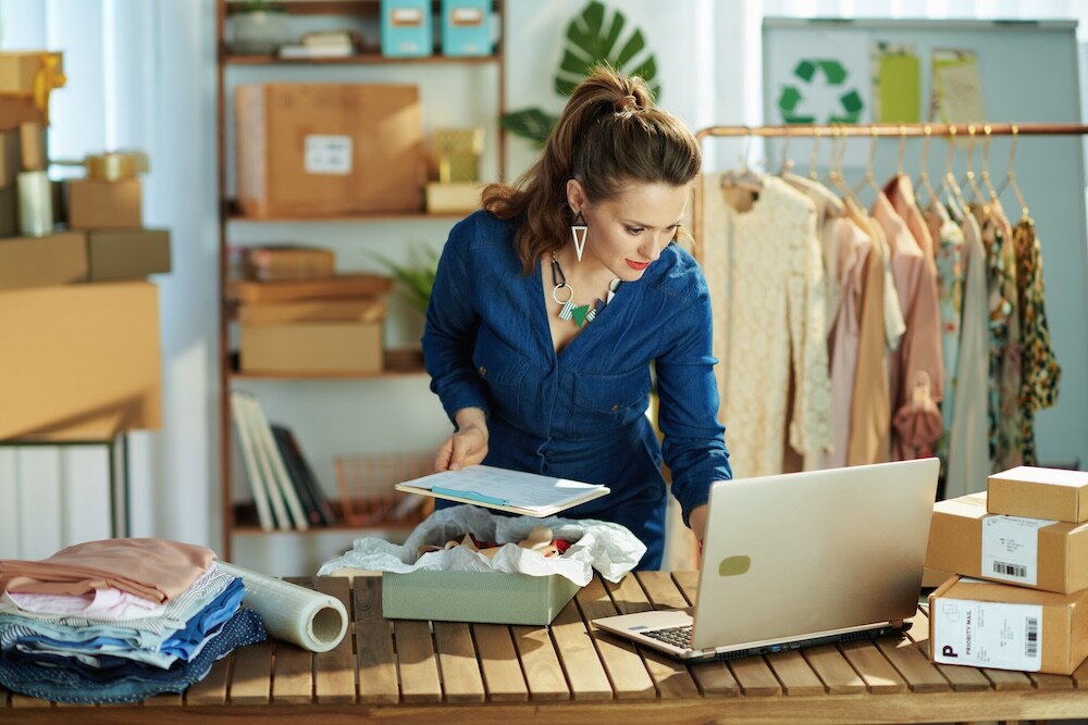 Woman standing at desk looking at laptop