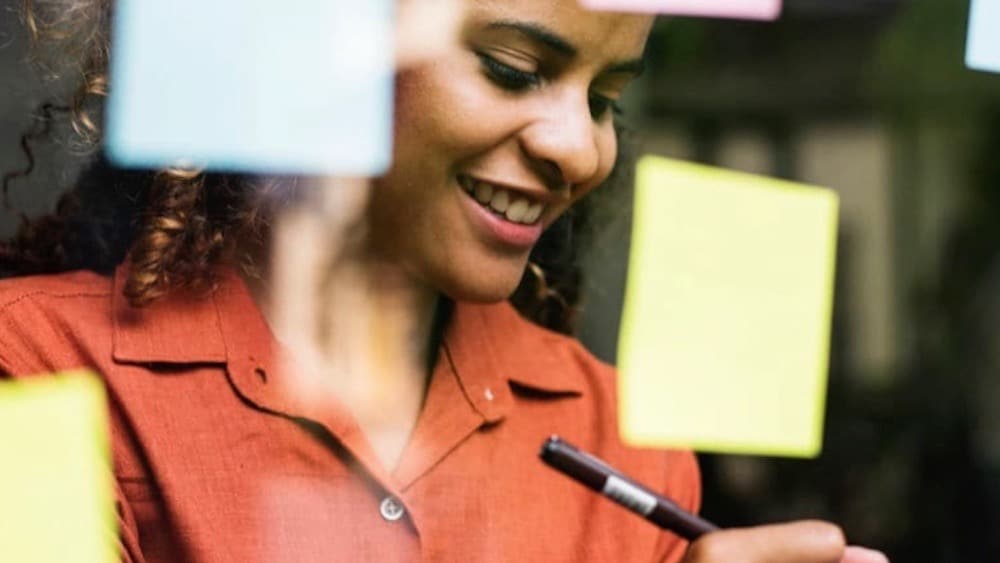 Person writing on post-it note