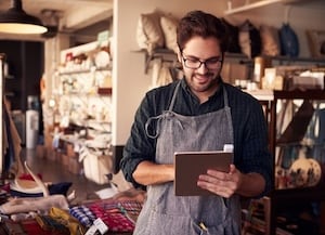Man standing in a store looking at a tablet in his hand