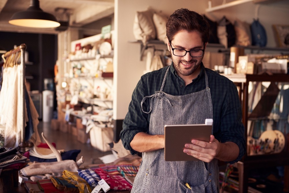 Man standing in a store looking at a tablet in his hand