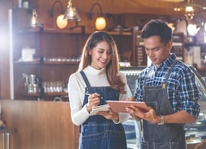 two people standing in restaurant looking at tablet