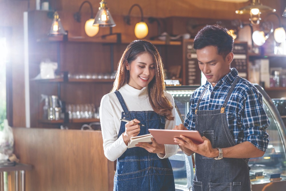 Man and woman standing in a restaurant staring at tablet