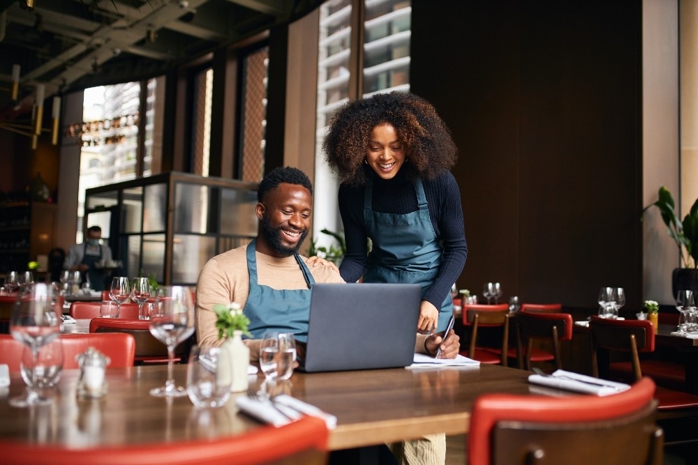 Man and woman in a restaurant staring at laptop