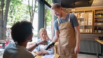 Person paying with contactless digital wallet at restaurant table