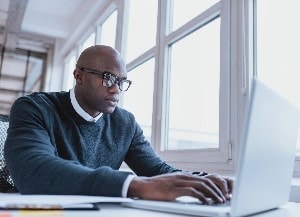 person sitting at desk looking at laptop