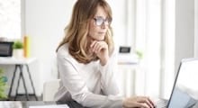 woman sitting at desk looking at laptop