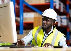 Construction worker at desk looking at monitor