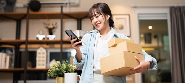 Woman holding boxes while looking at phone
