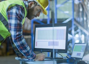Construction worker at desk looking at monitor