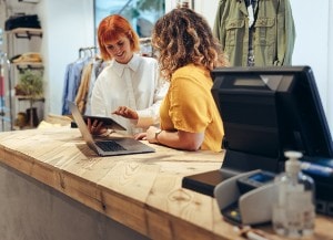 Two people behind the register at a retail store
