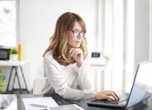 person sitting at desk looking at laptop