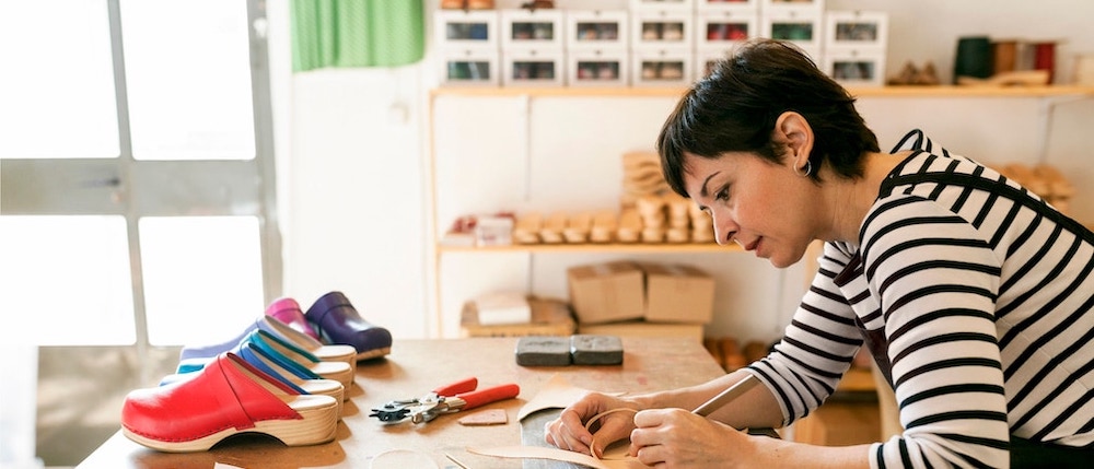 Woman at workshop table making shoes