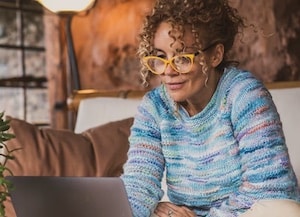 Woman sitting on couch looking at laptop
