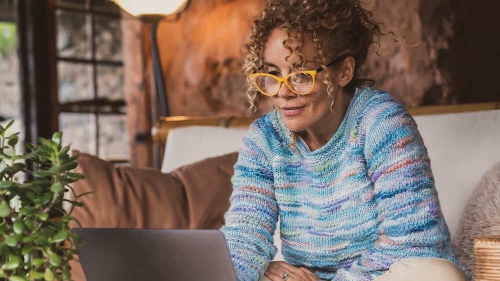 Woman sitting on couch looking at laptop
