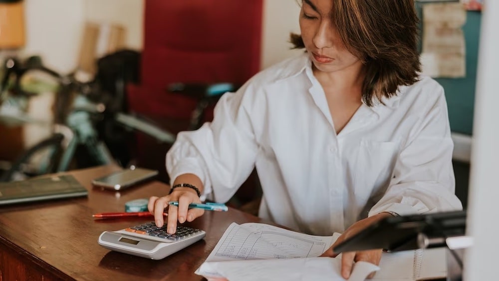 Woman at desk using calculator