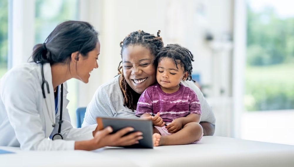 Mother and daughter in doctor's office with doctor looking at tablet