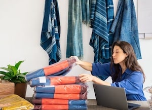 Woman at desk with laptop and merchandise 