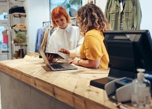two women on laptap behind retail counter