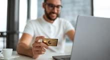 person at desk with laptop holding Amex card