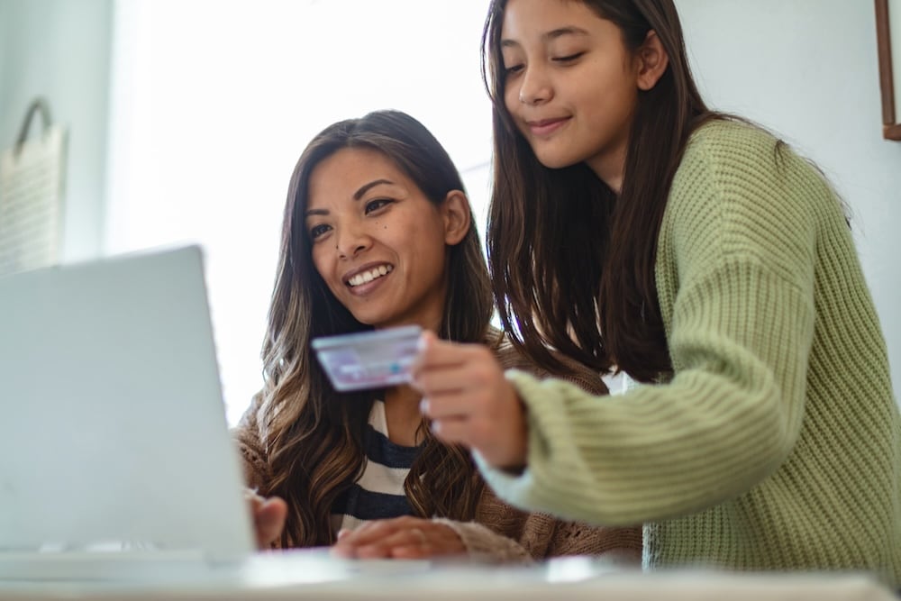 Two people looking at laptop with one woman holding credit card