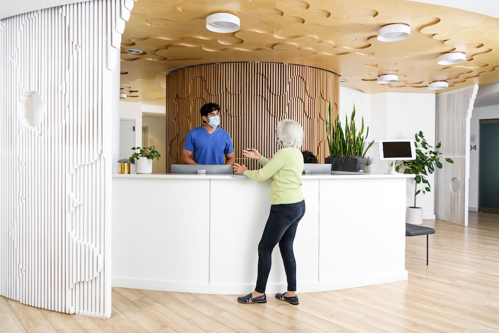woman standing at check-in desk with medical professional behind desk