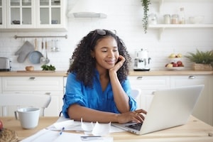 Woman on laptop sitting at kitchen table