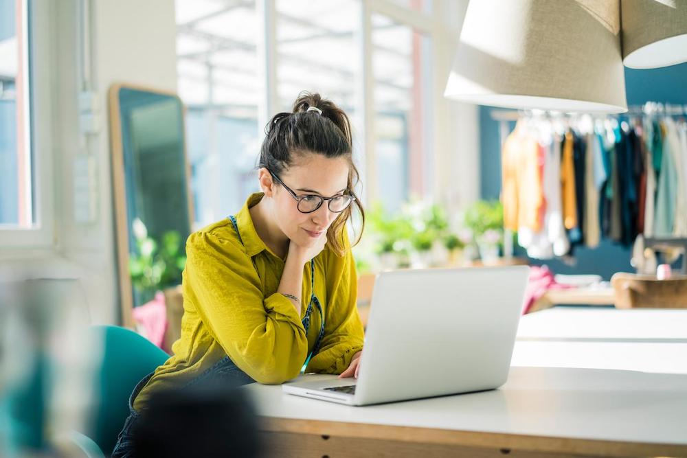 Small business retail owner sitting at table and looking at laptop