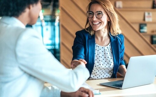 Two people shaking hands sitting at a desk
