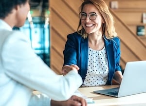 two people shaking hands sitting down at a desk