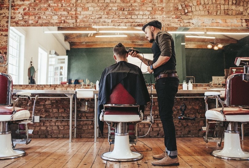 Hairdresser cutting man's hair in barber shop