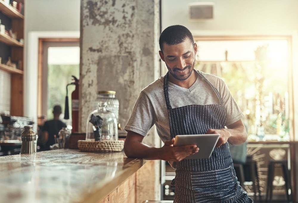 Small business owner standing at counter and looking at tablet device