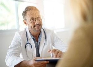 Healthcare professional at desk holiding tablet looking at someone