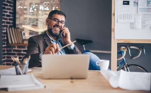 Man sitting at desk while on the phone
