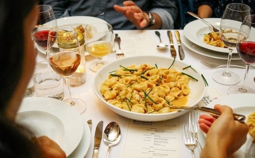 dining table with bowl of pasta and wine